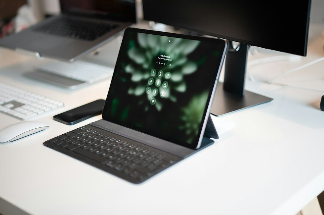 Open notebook and laptop on a wooden desk in a bright office